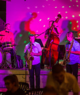 Banda en vivo actuando en un escenario iluminado en Le Camp de Florence, parque vacacional en Occitania.