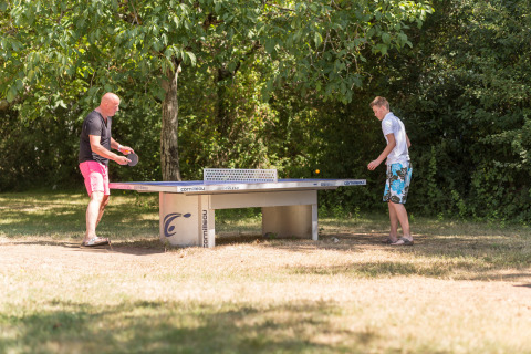 Dos personas juegan tenis de mesa al aire libre en el parque vacacional Le Camp de Florence, Occitania, Francia.