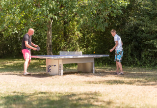 To personer spiller bordtennis udendørs ved Le Camp de Florence feriepark i Occitanie, Frankrig.