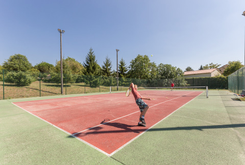 Dos personas juegan al tenis en una pista exterior en Le Camp de Florence, un parque vacacional en Occitanie, Francia.
