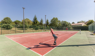 Dos personas juegan al tenis en una pista exterior en Le Camp de Florence, un parque vacacional en Occitanie, Francia.