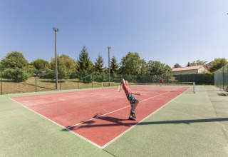 Deux personnes jouent au tennis sur un court extérieur à Le Camp de Florence, un parc de vacances en Occitanie, France.