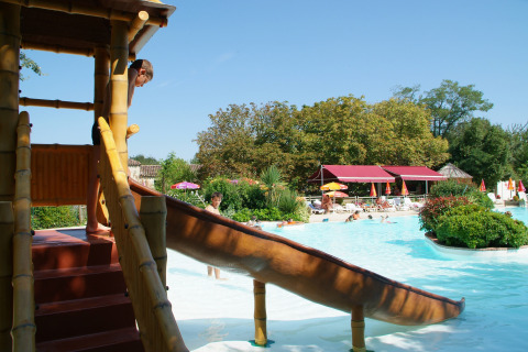 Bambini giocano sullo scivolo accanto alla piscina al parco vacanze Le Camp de Florence in Occitania, Francia.