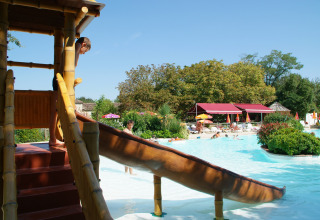Bambini giocano sullo scivolo accanto alla piscina al parco vacanze Le Camp de Florence in Occitania, Francia.