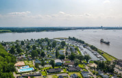 Luchtfoto van een vakantiepark met glampingaccommodaties, zwembaden en een jachthaven aan een rivier.