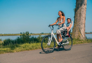 Mutter mit Tochter auf dem Rücken eines Fahrrads am Wasser entlang - EuroParcs De Biesbosch - Dordrecht, Südholland, Niederlan