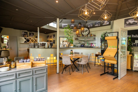 Gezellige bar in een glamping vakantiepark met moderne verlichting, zitruimte en drankjes aan de toog.