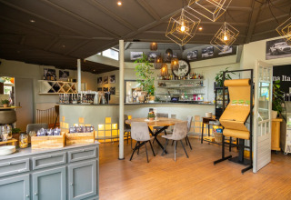 Gezellige bar in een glamping vakantiepark met moderne verlichting, zitruimte en drankjes aan de toog.