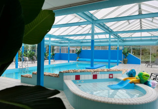 Overdekt zwembad met kinderbad, glijbaan en ligstoelen bij een vakantiepark dat glamping aanbiedt.