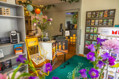 Ontvangstruimte bij een vakantiepark met glamping, folders, bloemen en kleurrijke lantaarns.