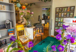 Ontvangstruimte bij een vakantiepark met glamping, folders, bloemen en kleurrijke lantaarns.