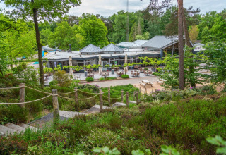 Buitenaanzicht van een vakantiepark met glamping voorzieningen, omringd door groen en terrassen in Vlaanderen.