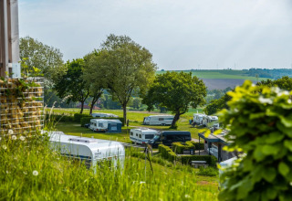Landschapsfoto van een vakantiepark met glamping, caravans en campers omringd door groene natuur.