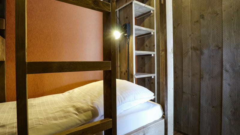 Habitación acogedora de lodge con litera de madera, escalera y luz cálida, decorada en tonos naturales.