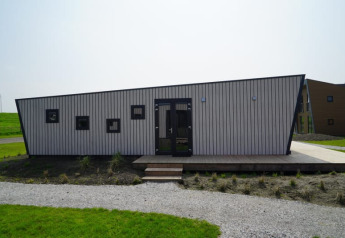 Foto di una tiny house moderna con tetto inclinato e finestre quadrate, situata in un'area erbosa.