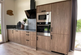 Petite cuisine moderne de lodge avec placards bois, four et micro-ondes encastrés, déco et comptoir noir.