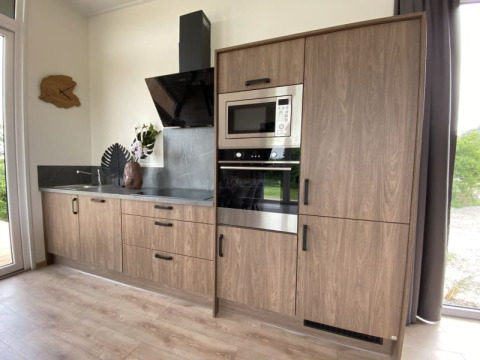 Moderne keukenkast in een lodge met houten kasten, inbouwoven, microgolf, zwart werkblad en decoratie.