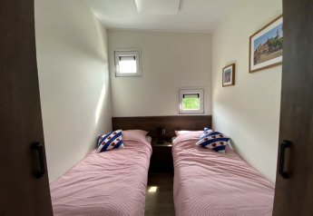 Photo of a lodge room with two single beds, pink bedding, artistic pillows, and framed wall art.
