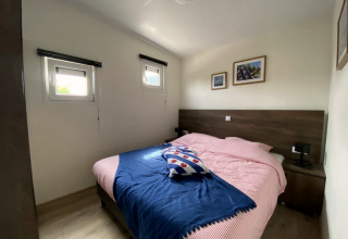 Photo d'une chambre confortable dans un lodge, avec lit double, deux fenêtres et tableaux muraux.