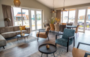 Espace salon-salle à manger d’une lodge moderne avec grandes baies vitrées et mobilier élégant, vue terrasse.
