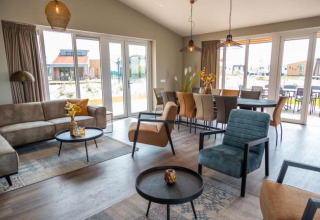 Espace salon-salle à manger d’une lodge moderne avec grandes baies vitrées et mobilier élégant, vue terrasse.