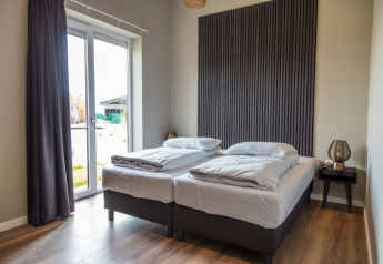 Moderne hotelværelse i en lodge med to enkeltsenge, store vinduer, træpanelvæg og natbord.