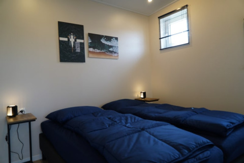 Habitación acogedora en una cabaña con dos camas individuales, ropa de cama azul oscuro y arte en la pared.