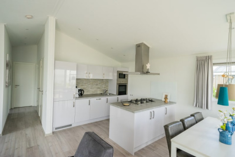 Modern kitchen and dining area in a lodge, featuring white cabinets, dining table, and large window.