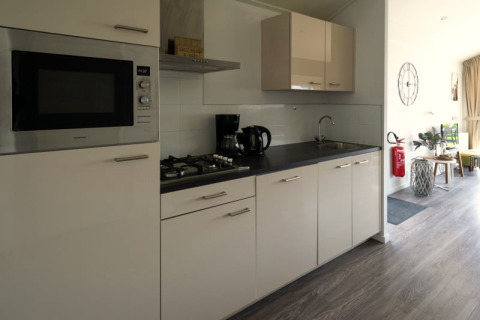 Küche in einer Lodge mit Herd, Mikrowelle, Kaffeemaschine und hellem, modernen Interieur.