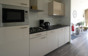 Modern lodge kitchen featuring a stove, microwave, coffeemaker, sink, and a bright living area beyond.