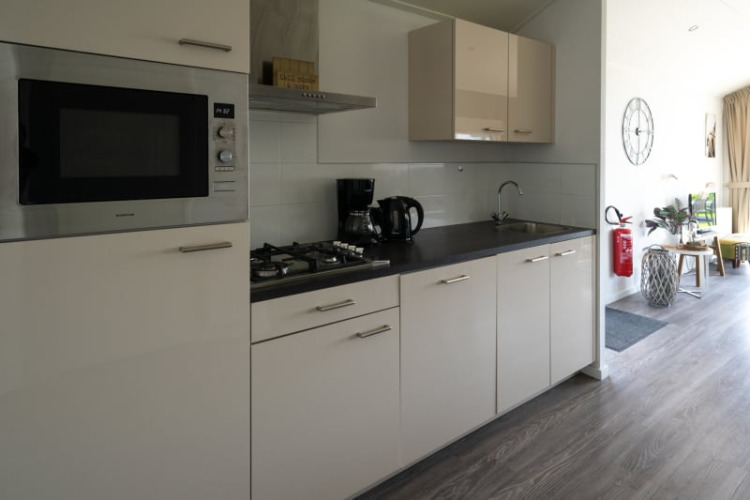 Cocina moderna en una cabaña con estufa, microondas, cafetera y detalles interiores luminosos.