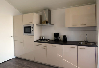 Moderne lodge-keuken met witte kasten, inbouwoven, kookplaat, koffiemachine en roestvrijstalen spoelbak.