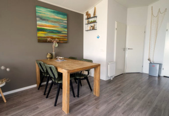 Gezellige eetruimte in een lodge met houten tafel, vier stoelen, wanddecoratie en moderne vloer.