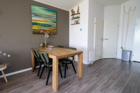 Acogedor comedor en una cabaña con mesa de madera, cuatro sillas, arte en la pared y decoración moderna.