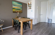 Cozy lodge dining area with a wooden table, four chairs, abstract wall art, and modern flooring.