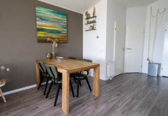 Et hyggeligt spiseområde i en lodge med et træbord, fire stole, vægkunst og moderne gulv.