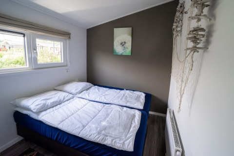 Acogedor dormitorio en una cabaña con dos camas individuales unidas, ropa de cama blanca y decoración moderna.
