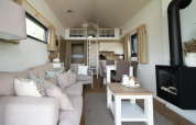 Moderne lodge met gezellige bank, haard, eettafel, open keuken en een slaapzolder met ladder.