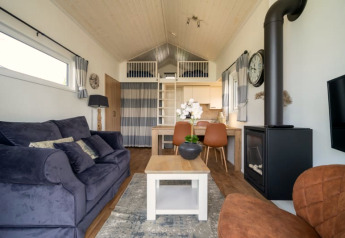 Séjour de lodge moderne avec canapé confortable, table à manger, cheminée, mezzanine et déco épurée.