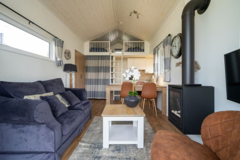 Salón moderno de lodge con sofá cómodo, mesa de comedor, chimenea, cama alta y decoración luminosa.