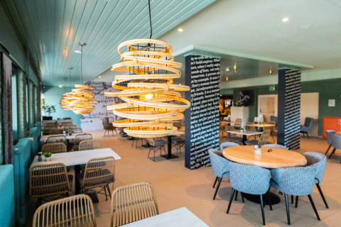 Modern ingerichte eetruimte met unieke hanglampen en comfortabele stoelen, in een vakantiepark voor glamping.