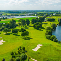 Luchtfoto van een vakantiepark met glamping, golfbaan, groen landschap en meer in Vlaanderen.