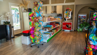 Interieur van een kleine winkel in een vakantiepark met snacks, dranken, ijs en kleurrijke strandballen.