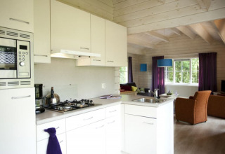 Moderne Küche und Wohnzimmer in einer gemütlichen Lodge mit Holzbalkendecke und großen Fenstern.