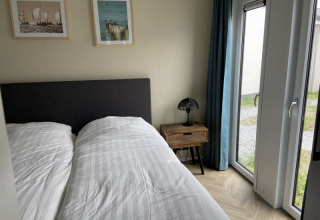 Camera da letto presso la lodge Pavilion con letto matrimoniale, comodino, lampada, quadri e terrazza.