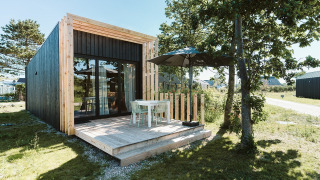 Casa pequeña moderna con terraza de madera y sombrilla en Holiday park De Klepperstee, Países Bajos