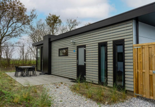Moderne lodge kaldet Pavilion med sort og grå facadestriber, terrasse og møbler i naturskønne omgivelser.