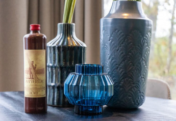 Dekorative Vasen und eine Flasche mit Etikett auf einem Tisch in der Pavilion Lodge, Natur draußen.