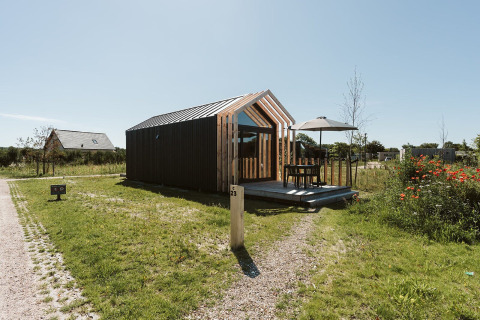 Casa diminuta moderna en Holiday park De Klepperstee, Países Bajos, con patio exterior y sombrilla.