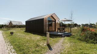 Casa diminuta moderna en Holiday park De Klepperstee, Países Bajos, con patio exterior y sombrilla.